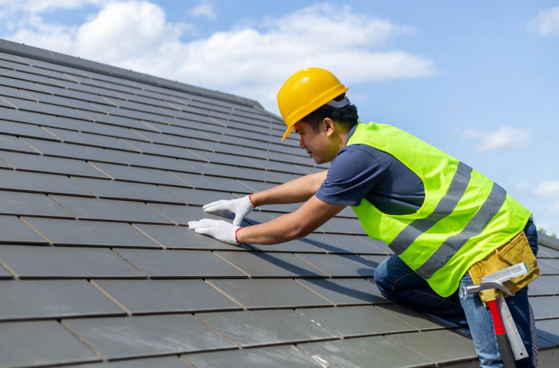 A roofer replacing shingles on a residential roof