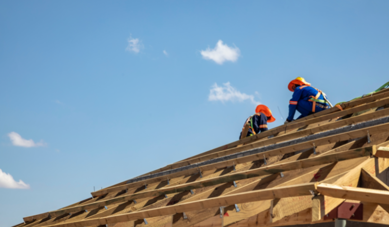 Two roofing contractors working at the top of the roof