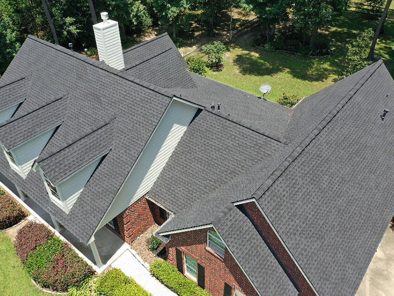 Aerial view of a residential home with a newly installed asphalt shingle roof by Lone Star Roofing in Houston TX